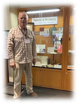 Ed Andersen standing in front of glass history exhibit